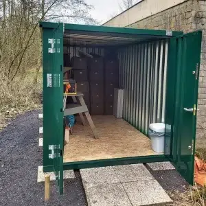 Groene container met open deuren en spullen erin