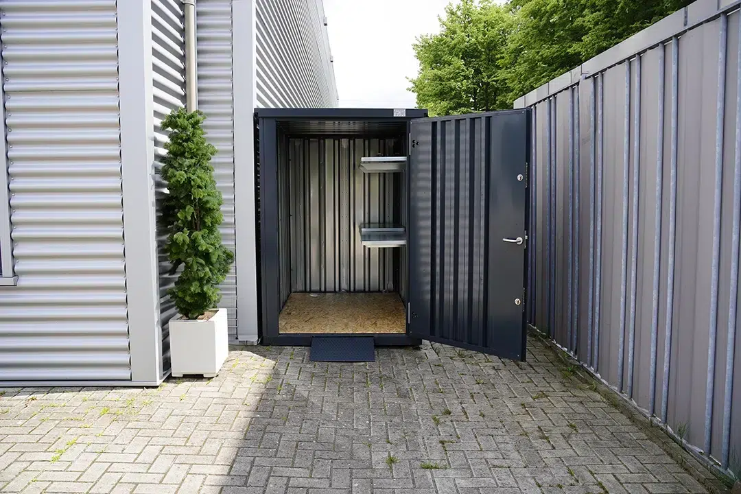 Tuincontainer naast een loods met een stelling
