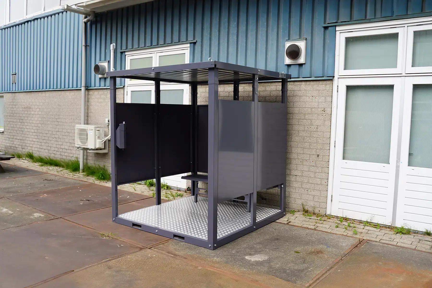 Rookcontainer in het antraciet naast een loods