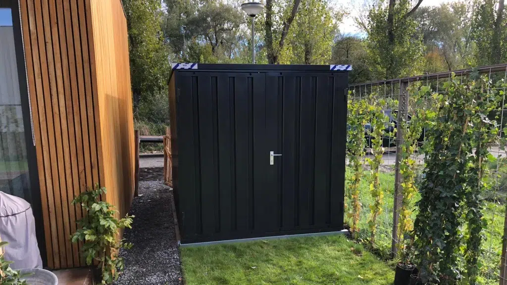 Foto van een zwarte bos container naast een vakantie huis